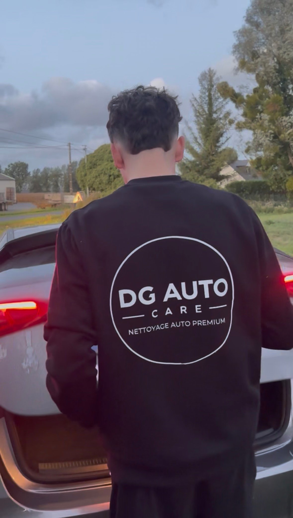 Hugo devant un véhicule, portant le sweat DG Auto Care